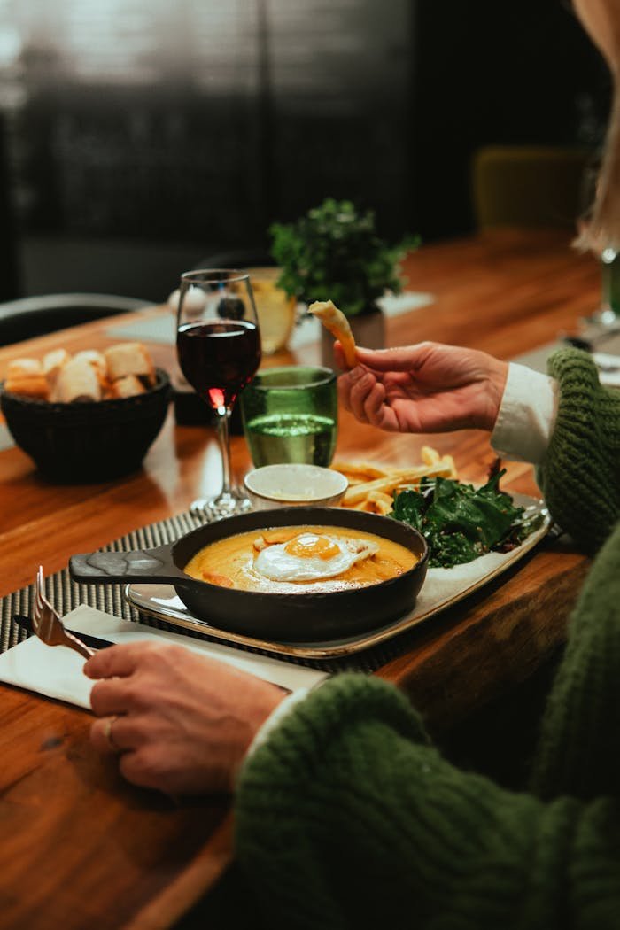 A delightful meal featuring cheese, wine, fries, and salad in a cozy French setting.